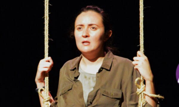 A woman with dark hair holds a hanging rope in either hand