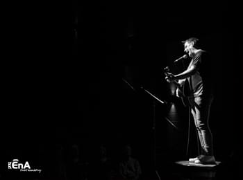 Black and white of a man standing on stage with a viold