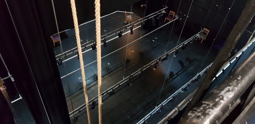 lightings bars suspended on ropes above a black stage