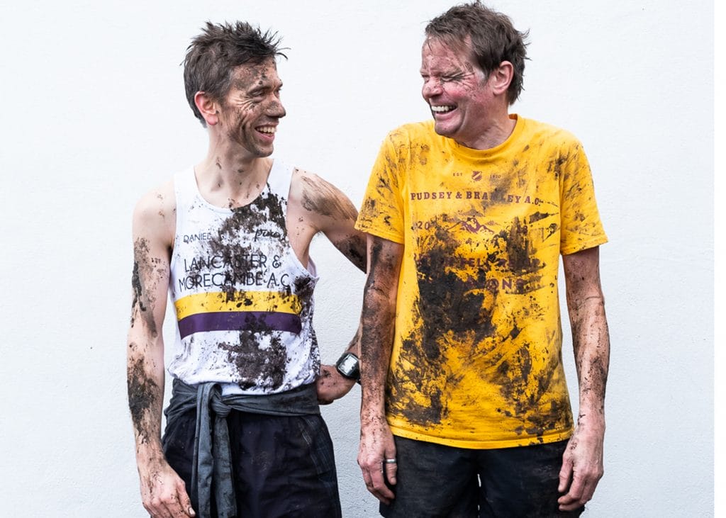 Daniel Bye and Boff Whalley in running attire. They are laughing and covered in mud.