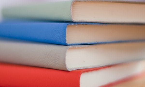 A stack of colourful notebooks on a wooden table.