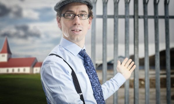 Daniel Bye in a cap and glasses, with hands outstretched in a storytelling pose