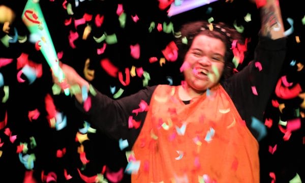 A person waving streamers with confetti falling around them