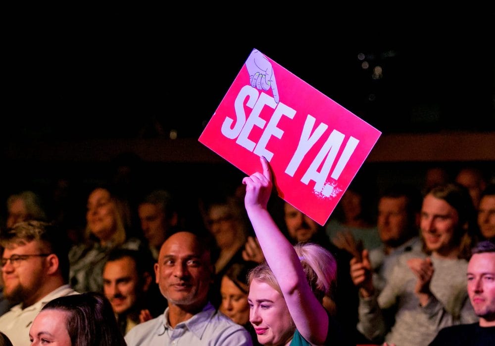 Beat The Gong event, person in crowd holding sign saying See Ya!