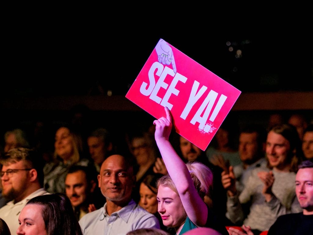 Beat The Gong event, person in crowd holding sign saying See Ya!