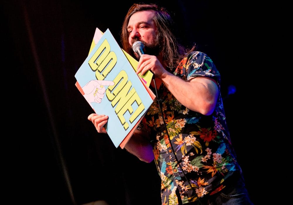 Matt Reed holding a gong sign that says "do one"