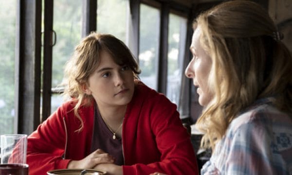 A young dark haired girl and an older blond woman sit having a conversation at a table