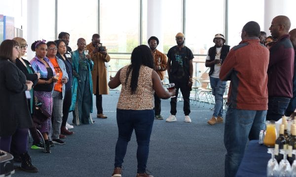 A group of attendees at a Harambee Pasadia event stand in a circle in ARC's second floor gallery space.