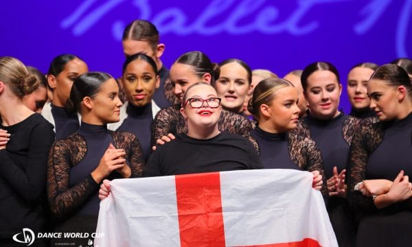 A group of dancers with one at the front holding an England flag