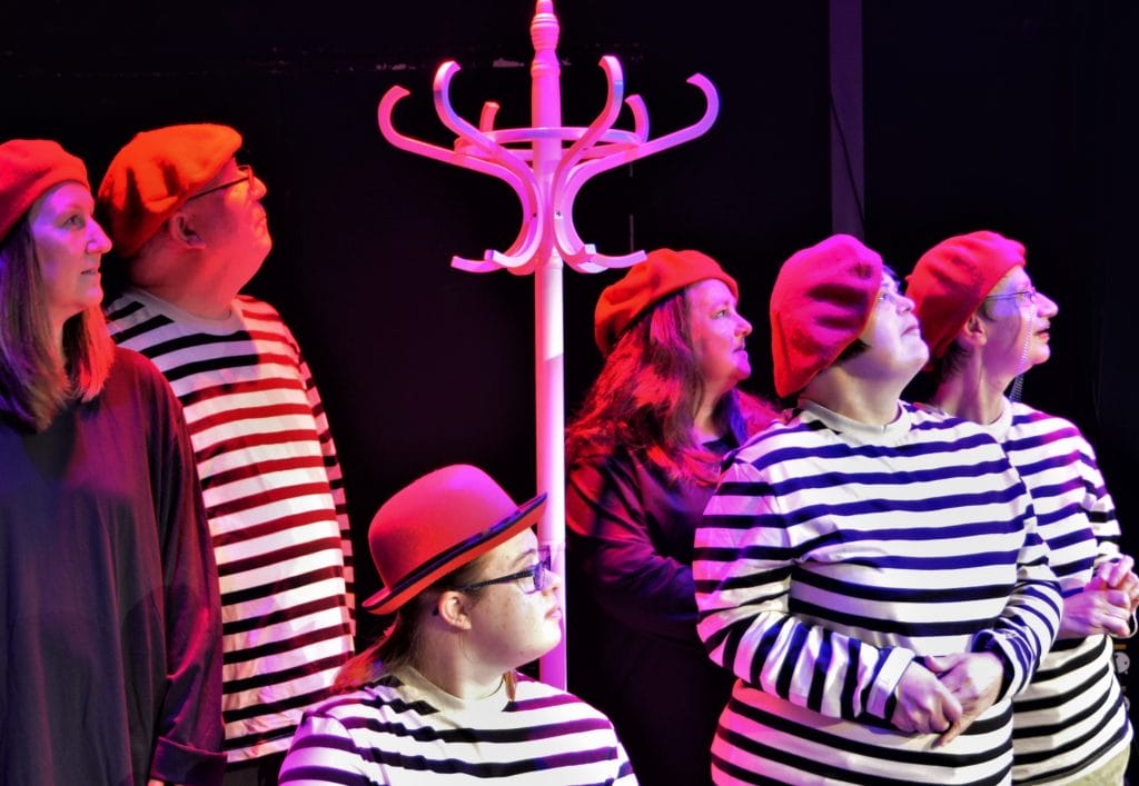 Six members of Full Circle Theatre Company gathered around a tall white hat stand