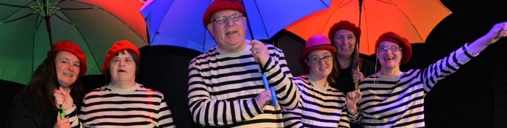 Full Circle actors in matching striped tops holding different coloured umbrellas