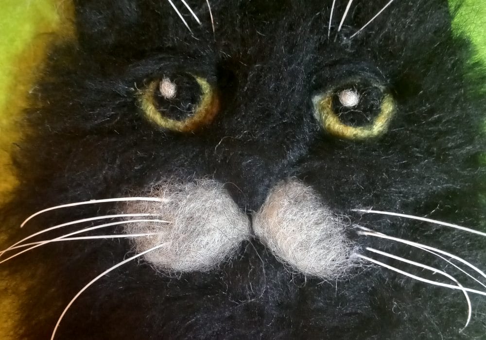 A 2d Needle Felt sculpture of a black cat.