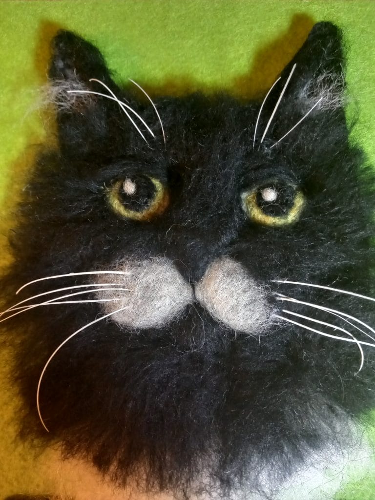 A 2d Needle Felt sculpture of a black cat.