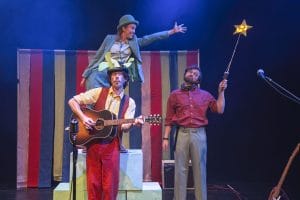 3 performers - one playing guitar, and a second reaching out to a star that the third performer is holding