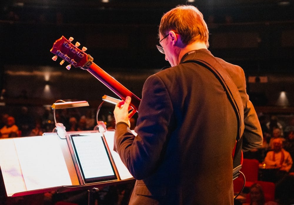 Paul from Pocket Jazz Orchestra playing guitar on stage