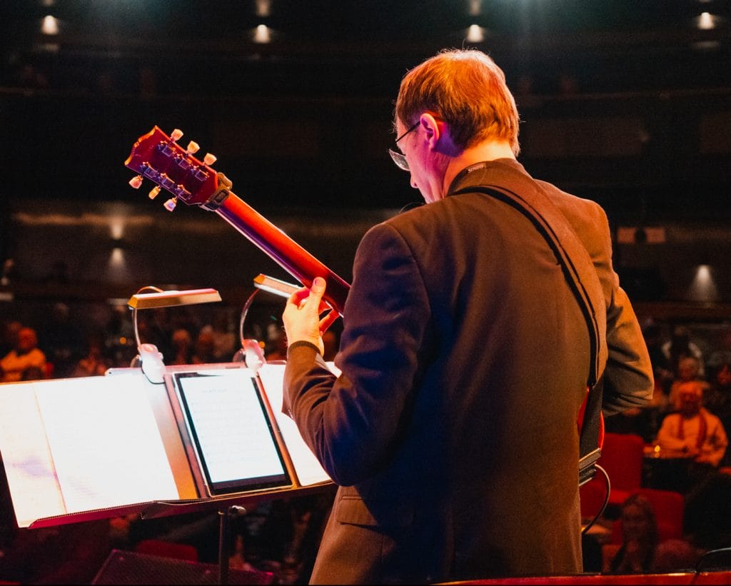 Paul from Pocket Jazz Orchestra playing guitar on stage