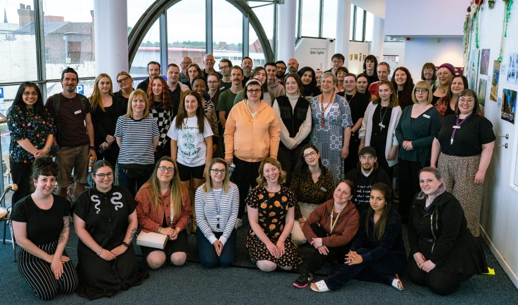 A large group of staff members pose for a photograph in ARC's second floor gallery.