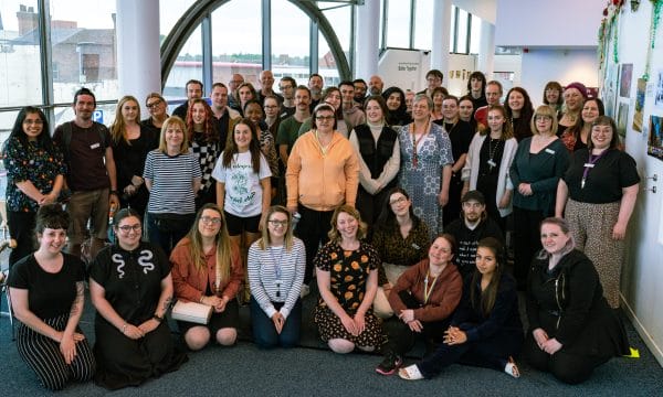 A large group of staff members pose for a photograph in ARC's second floor gallery.