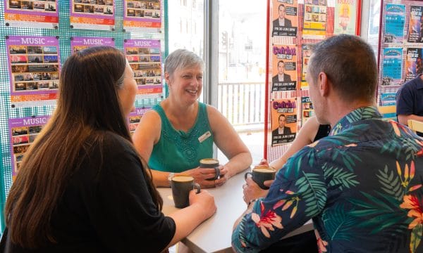 4 people sitting around a table in ARC's No 60 café, chatting and drinking coffee