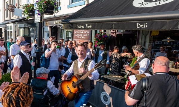 Mike playing guitar outside a bar with a crowd of people around him