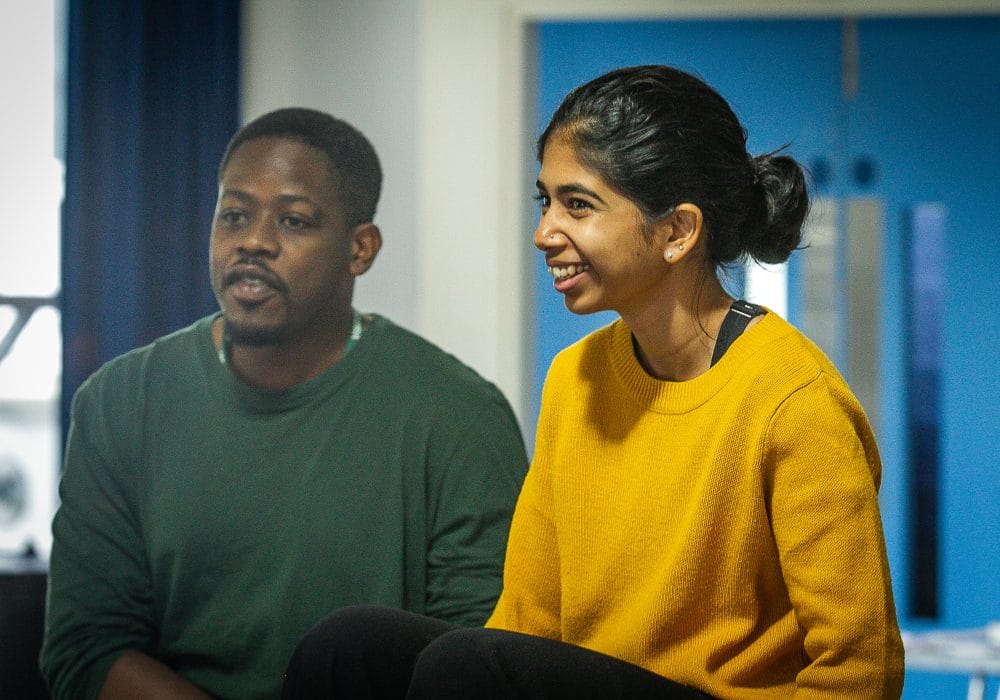 Divija Melally and Saili Katebe sitting alongside each other. Saili is wearing a dark green jumper and Divija is wearing a yellow jumper.