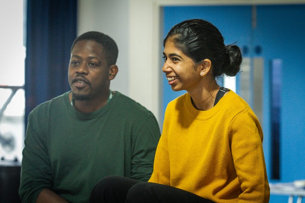 Divija Melally and Saili Katebe sitting alongside each other. Saili is wearing a dark green jumper and Divija is wearing a yellow jumper.