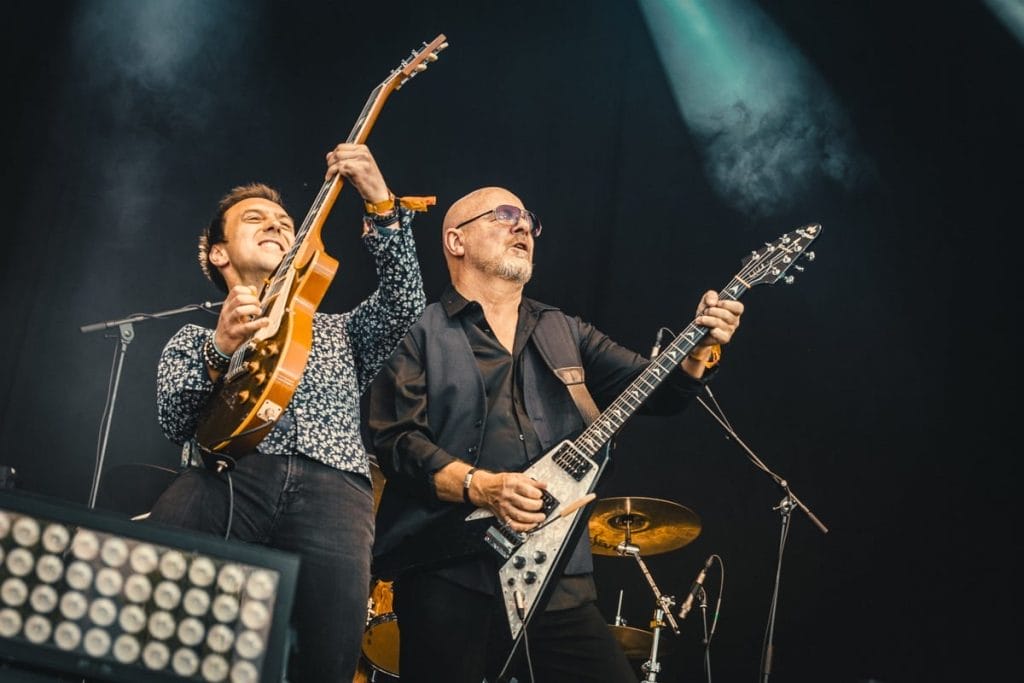 Two guitarists from Wishbone Ash including front person Andy Powell shred guitar together on stage