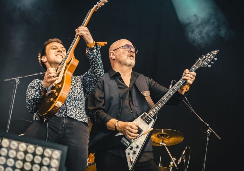 Two guitarists from Wishbone Ash including front person Andy Powell shred guitar together on stage