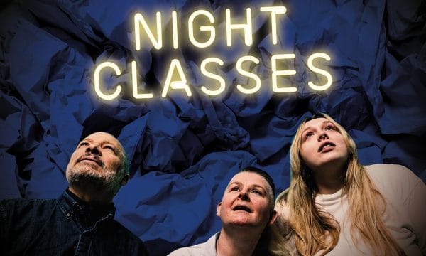 Three people looking upwards at a neon sign saying NIGHT CLASSES