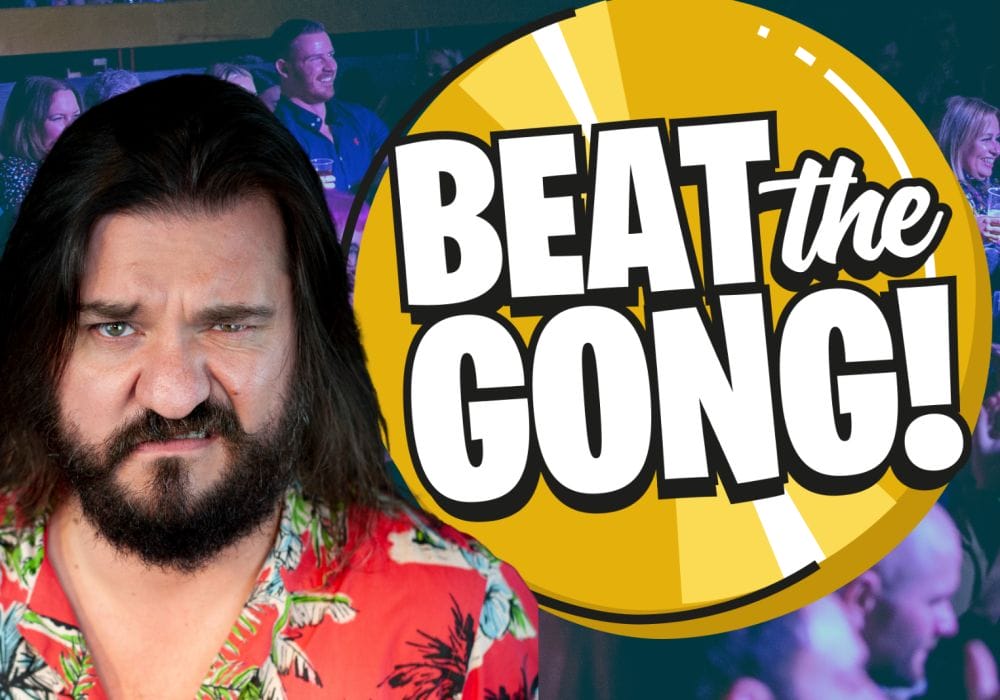 Matt Reed, a white comedian with mid-length dark brown hair, stands next to an animated Beat the Gong logo. He is looking directly into the camera and is wrinkling up his nose.