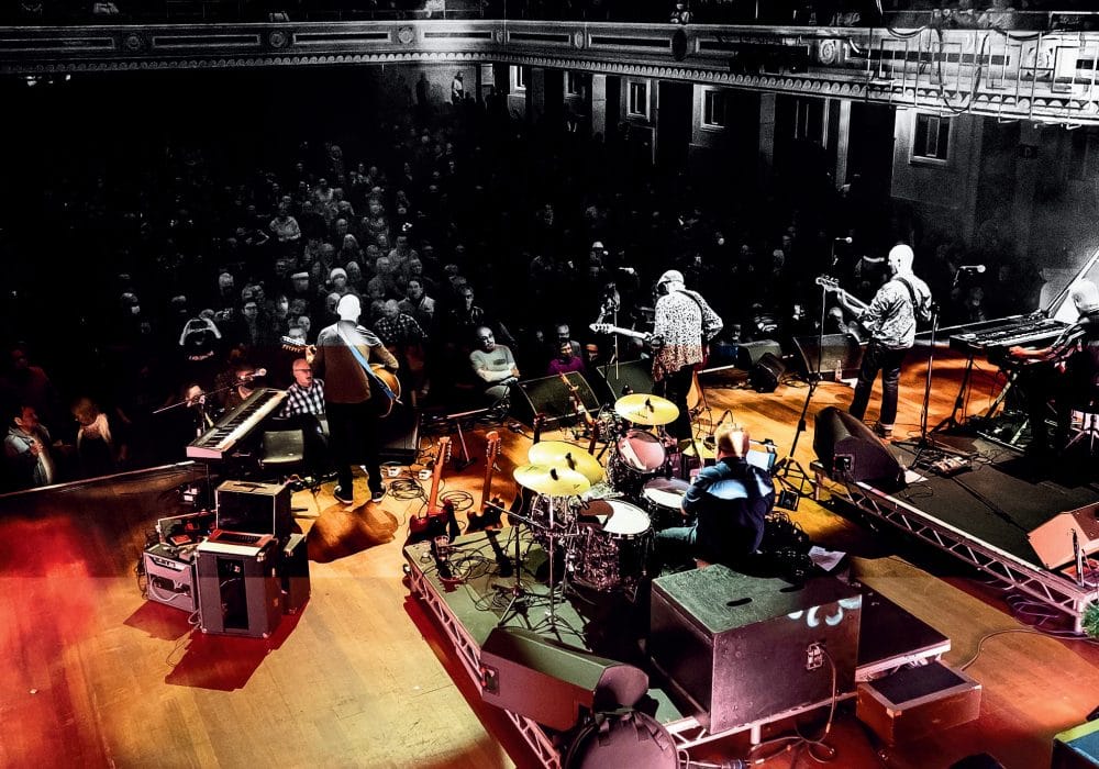 Lindisfarne band on stage in front of a busy crowd