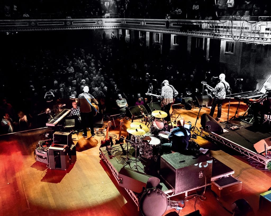 Lindisfarne band on stage in front of a busy crowd