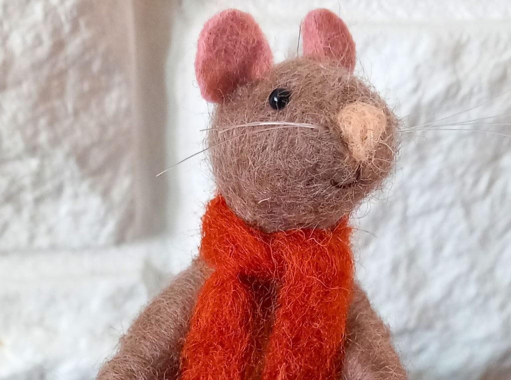 A brown, needle felt mouse wearing a red felt scarf.