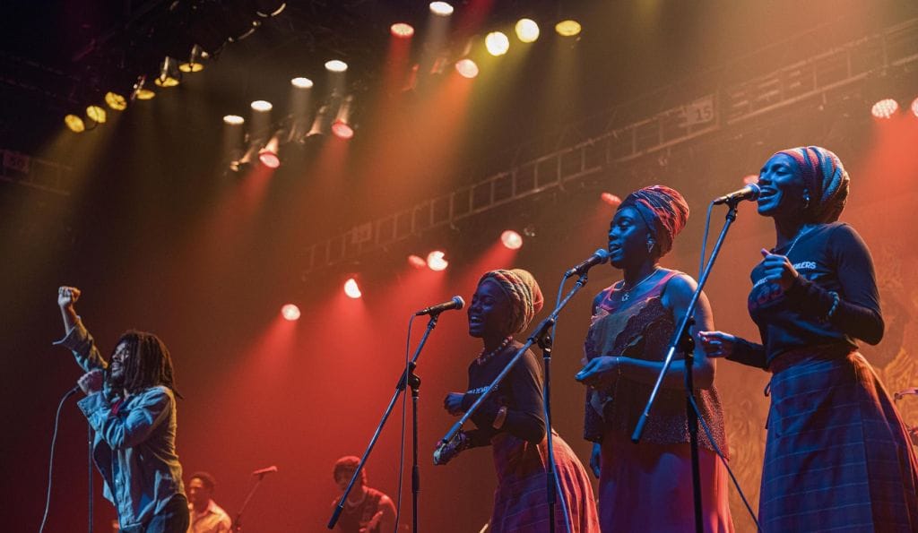 3 backup singers performing with Bob Marley who takes centre stage.