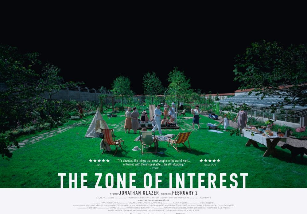 The Zone of Interest advertising poster showing people on a green lawn with tents and picnic chairs, to the left the barbed wire of Auschwitz