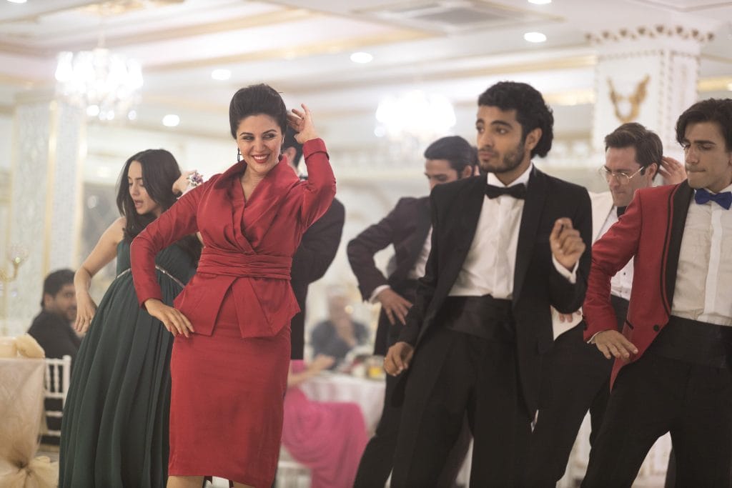 Leila's mother dancing with a group of people, looking very confident.