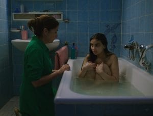 Elaha in sat knees up in a bath whilst her mother is knelt beside the bath.