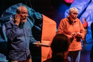 A performer and a BSL interpreter on the set of Night Classes with one member of the audience just visible in front of them