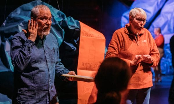 A performer and a BSL interpreter on the set of Night Classes with one member of the audience just visible in front of them