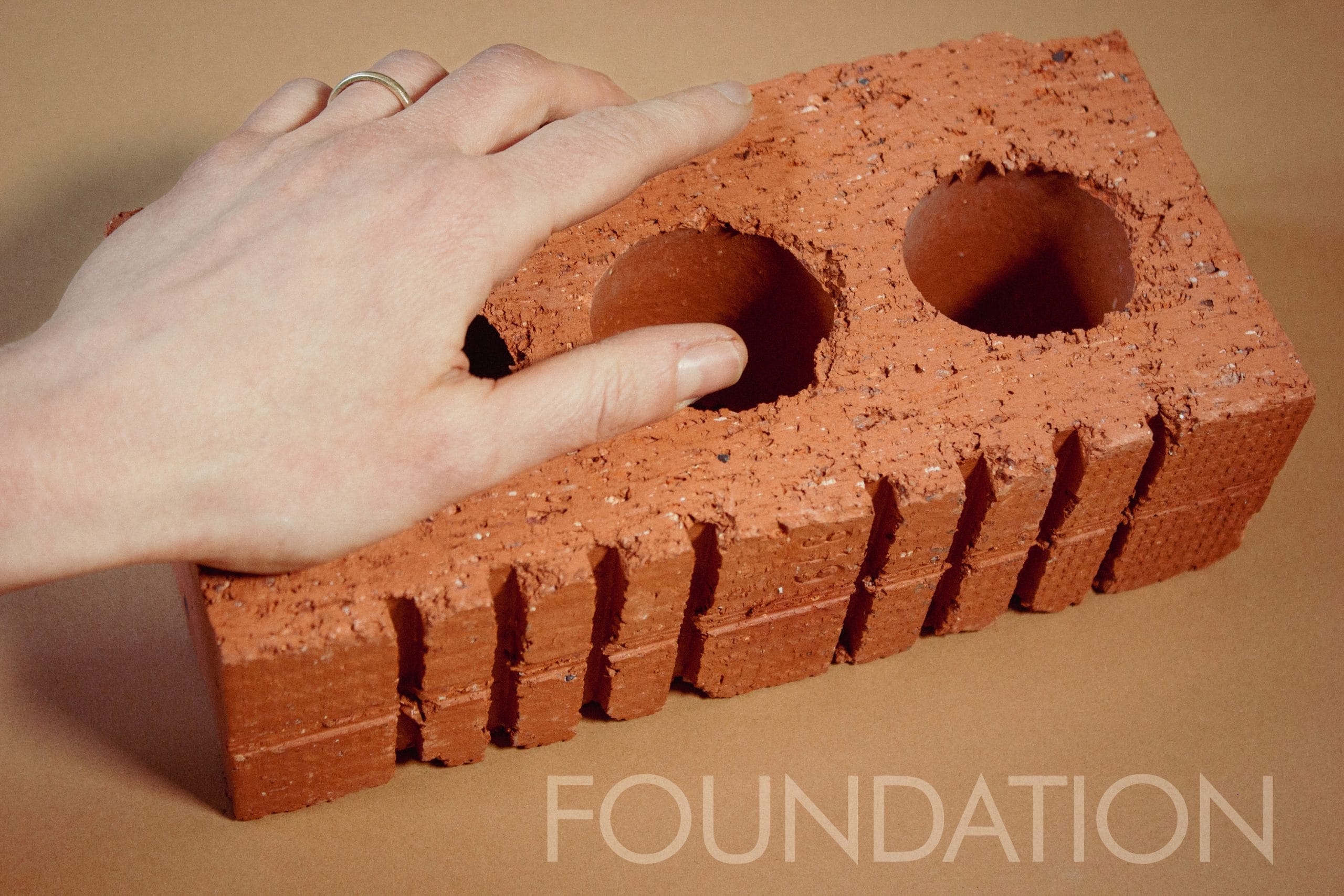 A hand on top of a red brick