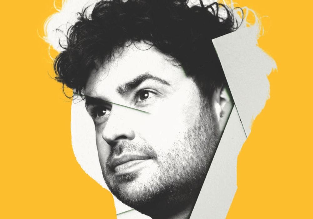 A black and white headshot of comedian Brennan Reece, against a bright yellow background.