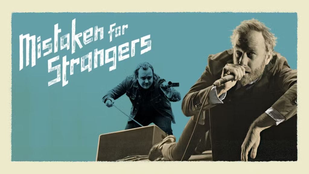 The singer Matt Berninger lounges to the right of the image, holding a microphone to his mouth. Behind him, the filmmaker Tom Berninger holds a handheld video camera. To the left of both men are the words Mistaken for Strangers.