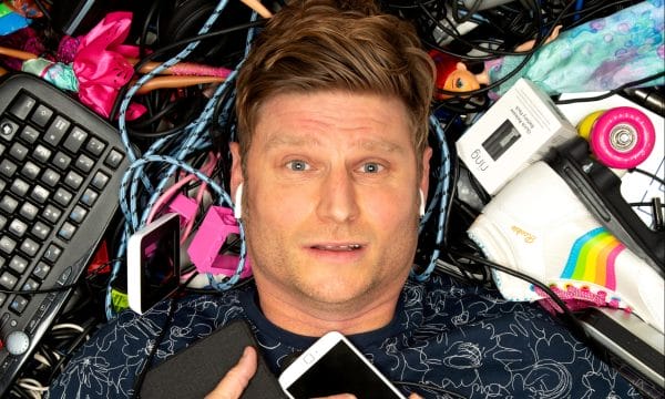 Comedian Scott Bennet lays on top of a pile of wires, keyboards, and other assorted electricals.