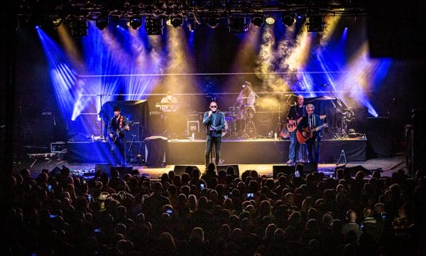 The band The Christians performing on a stage to a packed crowd.