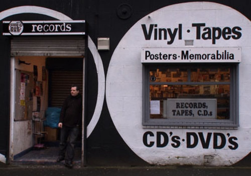 Sound It Out records shop front with owner stood on the step opening to the shop.