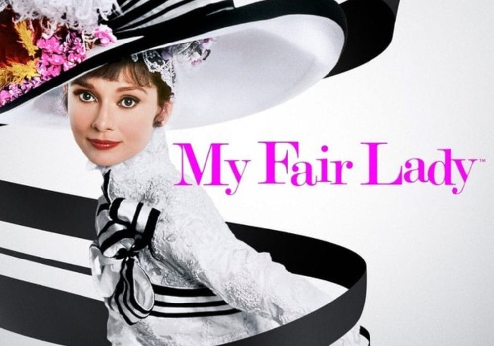 Actress Audrey Hepburn, wearing a large black and white hat. Pink text reads: My Fair Lady.