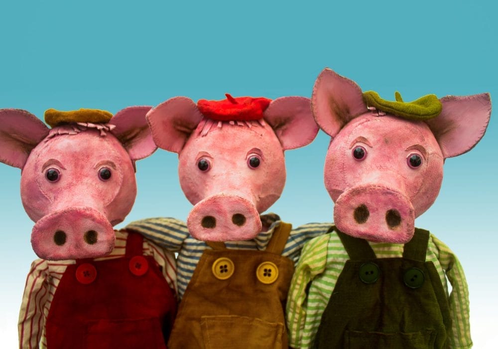 An image of three piglet puppets on a light blue background.