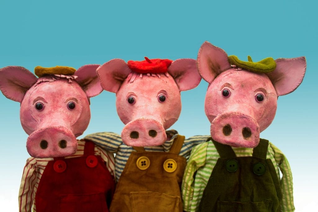 An image of three piglet puppets on a light blue background.