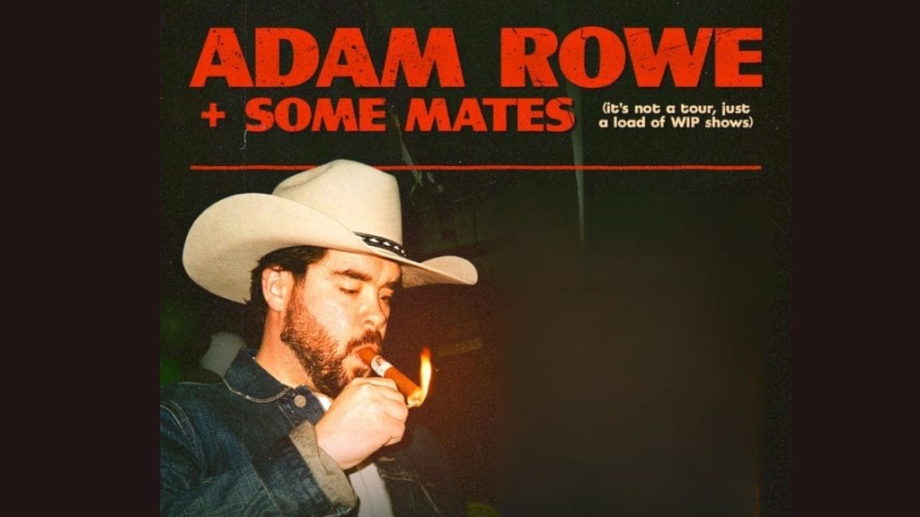 A man with beard wearing a white cowboy cat and is lighting a cigar