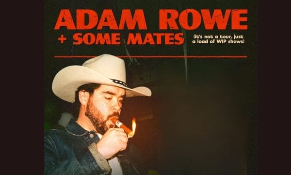 A man with beard wearing a white cowboy cat and is lighting a cigar